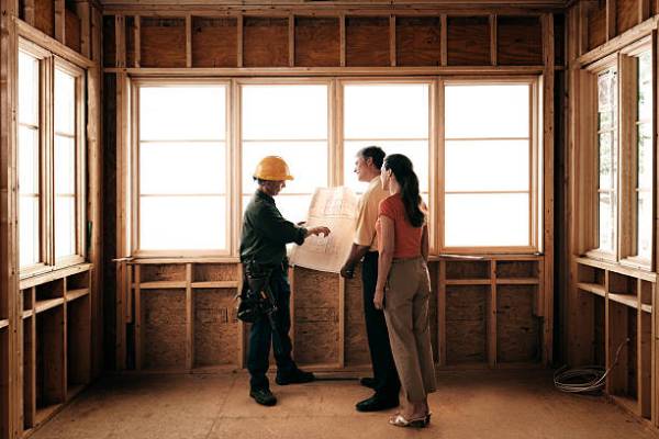 Husband and wife consulting with a architect inside a home under construction.